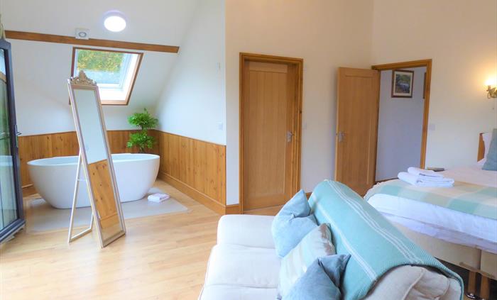Bedroom 1 (upstairs) with superking size bed or 2x single beds, sofa, smart TV and free standing bathtub. There is a covered balcony which looks over